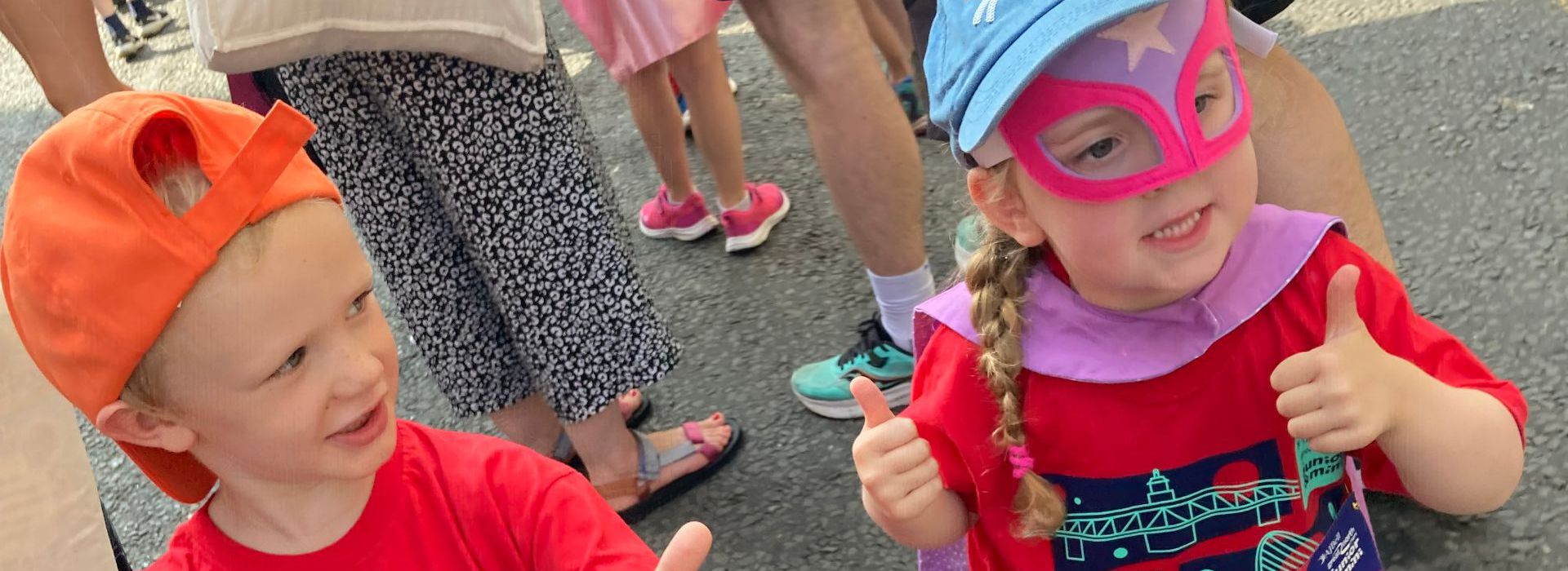 Girl dressed as superhero and boy wearing Maggie's cap running the Mini Great North Run
