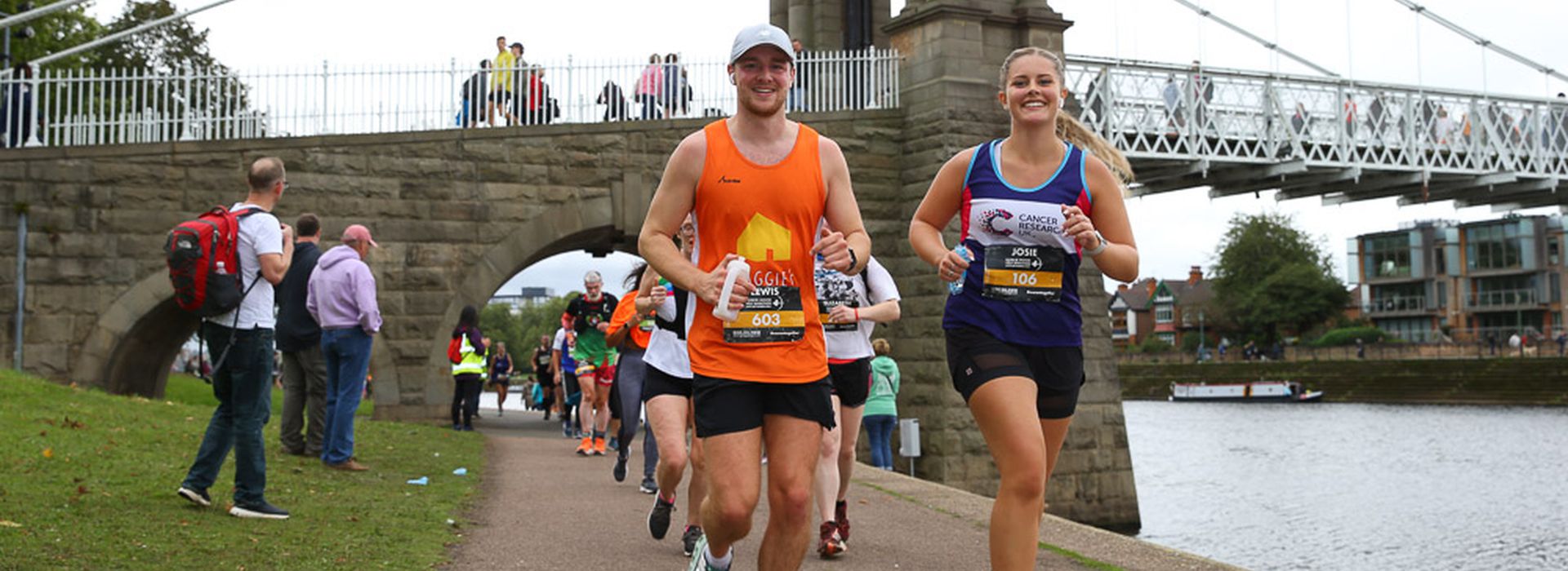 Young man and women running together and smiling along River Trent, Nottingham in Robin Hood Half Marathon