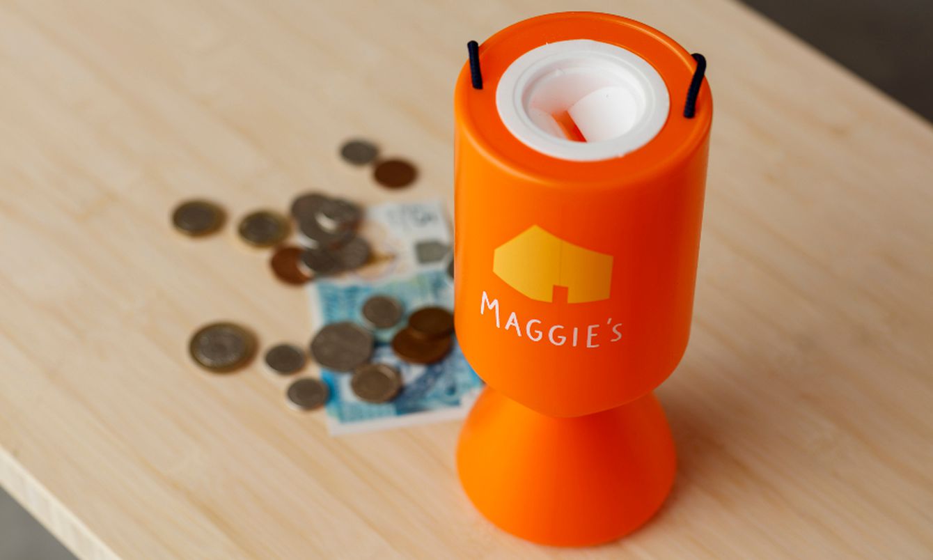 Maggie's collection box next to coins and £5 note